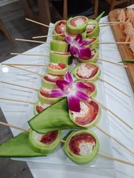Cucumber-wrapped sushi skewers with tuna, salmon and crab filling on a white platter, garnished with purple orchid — elegant sushi appetizer