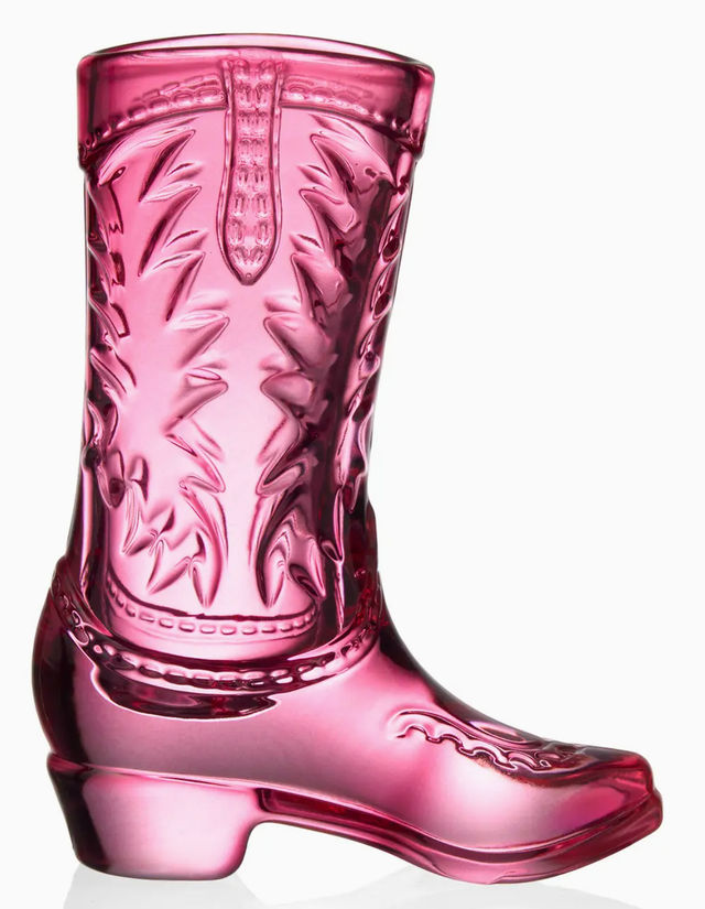 Shiny pink glass cowboy boot figurine with embossed western stitching and heel, decorative piece on white background
