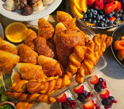 Golden croissants, pain au chocolat and twisted pastries on a colorful brunch platter with fresh berries, orange slices and smoked salmon
