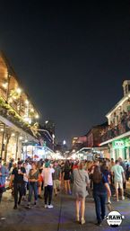 Lively nighttime crowd on New Orleans Bourbon Street with illuminated balconies, packed sidewalks, and people enjoying vibrant nightlife