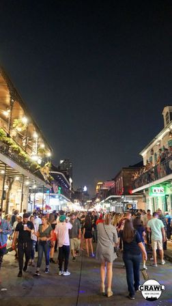 Lively nighttime crowd on New Orleans Bourbon Street with illuminated balconies, packed sidewalks, and people enjoying vibrant nightlife