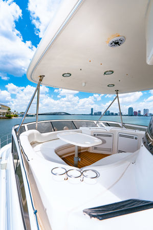 Sun-drenched luxury yacht seating area with table under a canopy, bay waters, bridge and city skyline under a bright blue sky