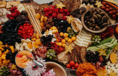 Vibrant artisanal charcuterie grazing board with assorted cheeses, cured meats, crackers, breadsticks, olives, and fresh and dried fruits — festive party platter.