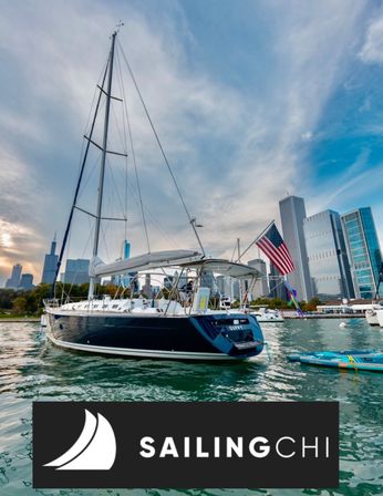 Sailboat with American flag anchored on Lake Michigan near the Chicago skyscraper skyline, paddleboards in the foreground and dramatic cloudy sky overhead.