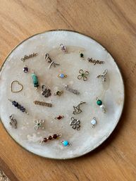 Flatlay of assorted tiny jewelry charms and colorful gemstone connectors on a round white onyx tray with gold rim, set on a wooden table — DIY jewelry supplies