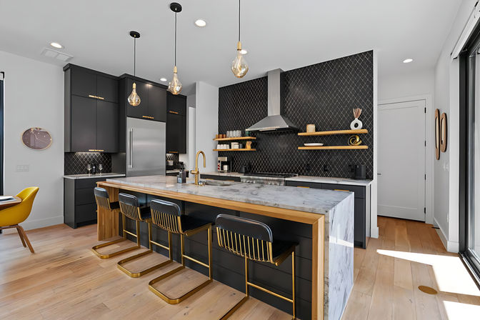 Contemporary open-concept kitchen with matte black cabinets, patterned tile backsplash, marble waterfall island, gold-accented bar stools and pendant lights on light hardwood floors.