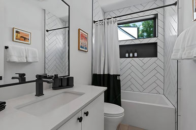 Contemporary small bathroom with white herringbone tile, matte black fixtures, white vanity sink, bathtub with black-and-white shower curtain and horizontal window