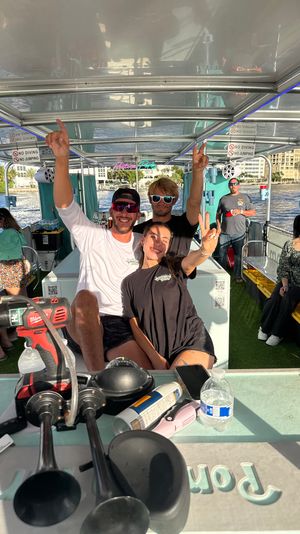 Cheerful group of friends flashing peace signs on a sunny pontoon boat cruise with a waterfront skyline and boating gear on the table