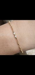 Close-up of a dainty gold bead bracelet with three sparkling textured silver beads worn on a wrist