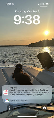 Brown dog lounging on the bow of a boat at golden sunset over a calm lake, with a smartphone lock screen time and notification banner overlay.