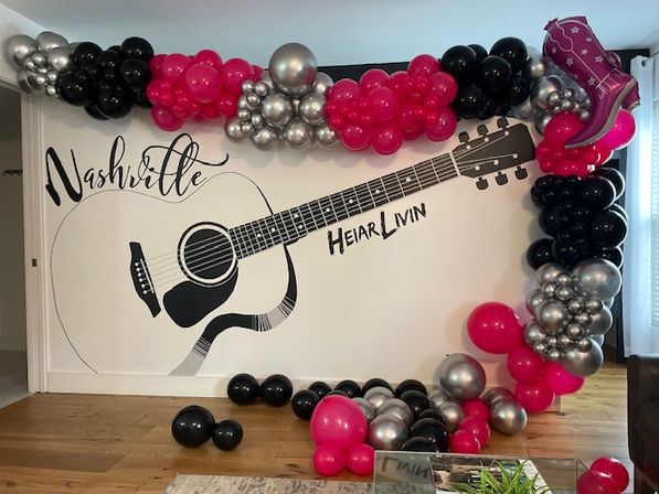 Nashville guitar wall mural framed by playful pink, black and silver balloon arch with a cowboy boot balloon