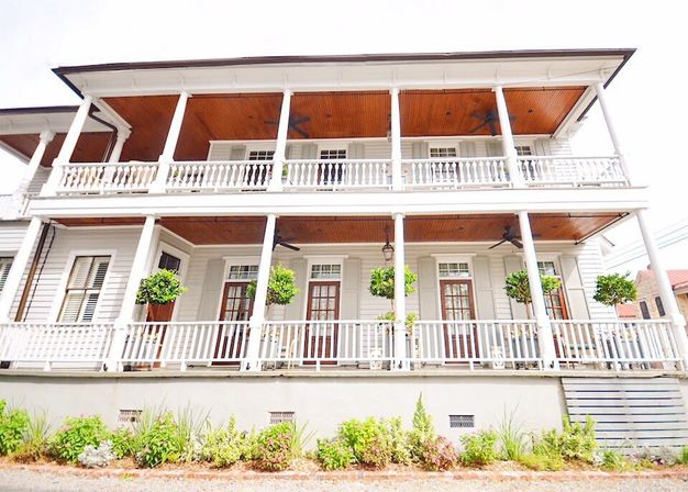 Charming Southern two-story white clapboard house with double-gallery porches, white balustrades, wood-paneled ceilings, hanging potted plants and tall French doors