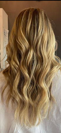 Back view of long sun-kissed blonde balayage hair with loose beachy waves, salon-style finish.
