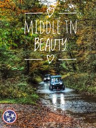 Autumn forest trail in Middle Tennessee with two off-road UTVs splashing through a shallow creek beneath colorful fall foliage, a fun outdoor adventure scene.