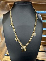 Gold chain necklace with sparkling heart charms and a small padlock-and-key pendant displayed on a black bust in a wooden jewelry display