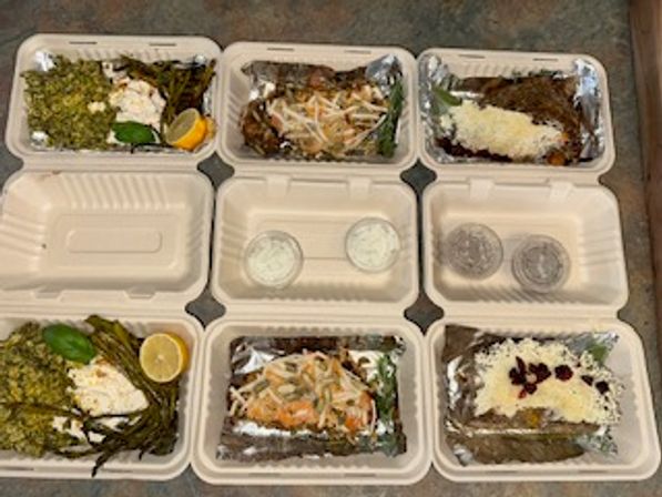 Six compostable takeout containers arranged in two rows with Mediterranean-style to-go meals: herb-seasoned rice with lemon, shredded cabbage salad, roasted vegetables, creamy white sauce toppings, and three small sauce cups in the center.