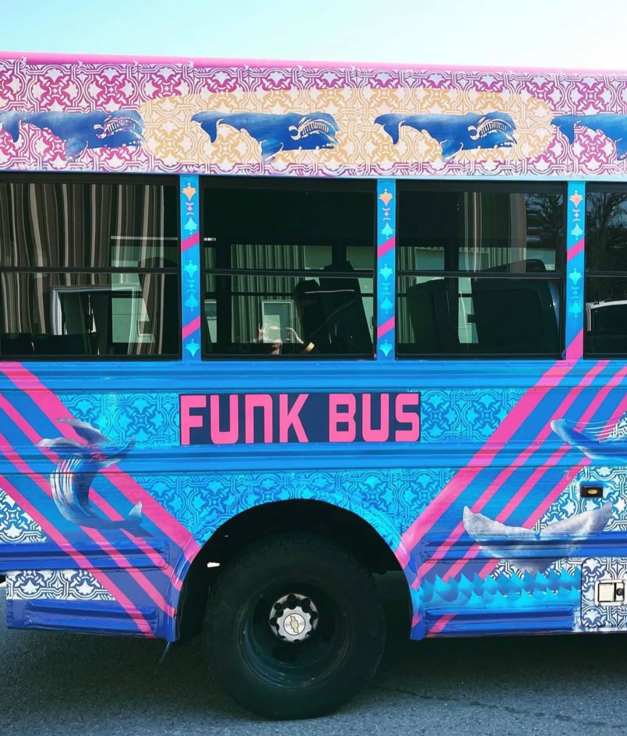 Bright blue and pink 'FUNK BUS' side view with ornate patterned panels, whale illustrations, diagonal stripes and a black wheel