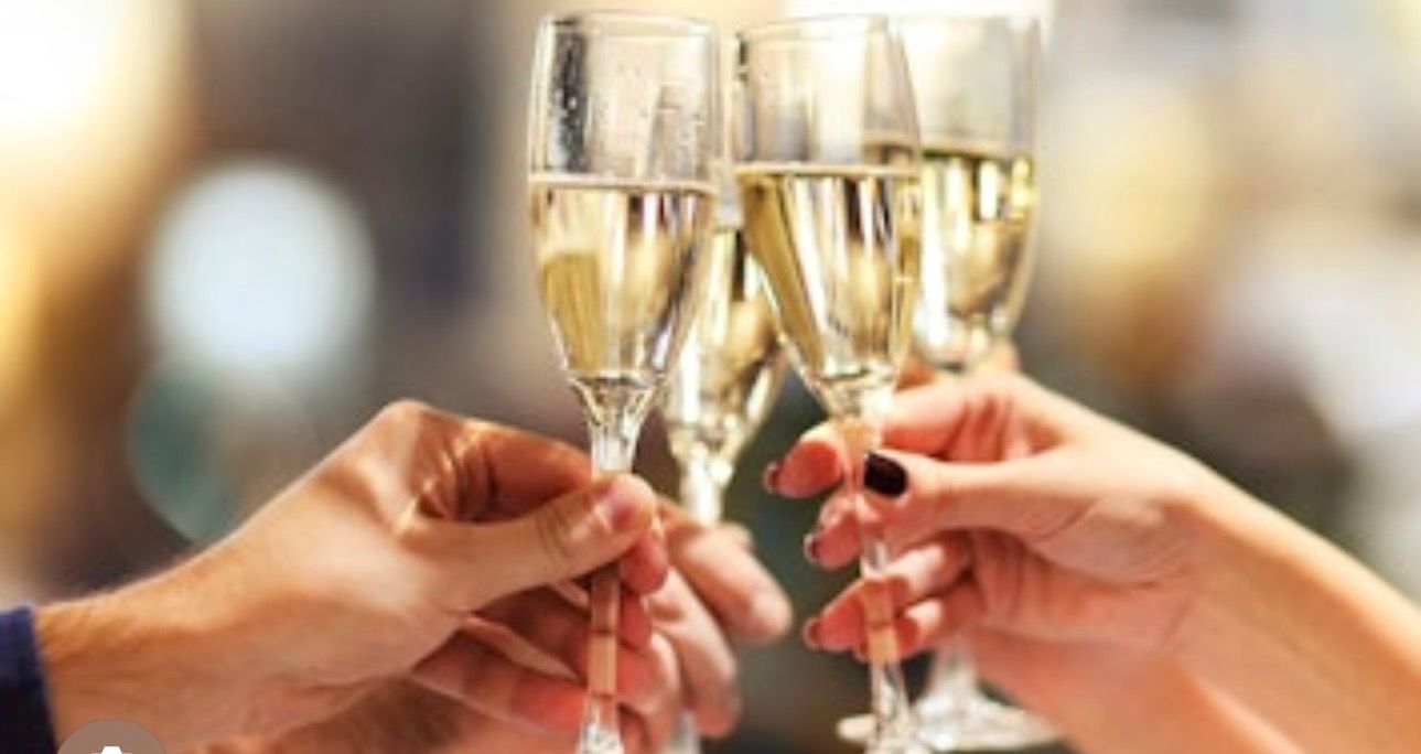 Close-up of four hands clinking champagne flutes in a celebratory toast at a festive event