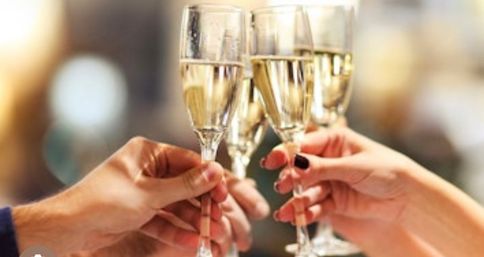 Close-up of four hands clinking champagne flutes in a celebratory toast at a festive event