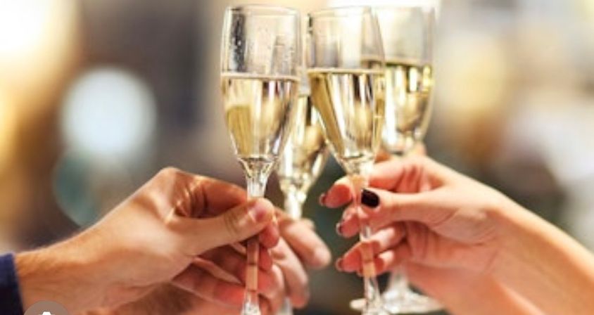 Close-up of four hands clinking champagne flutes in a celebratory toast at a festive event
