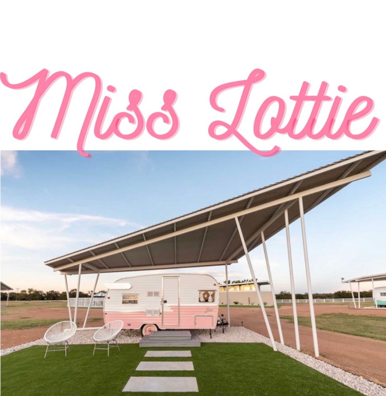 Pink retro camper sheltered by a slanted metal carport at a glamping-style site, two white outdoor chairs on green turf with concrete stepping stones and a pastel sky