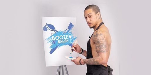 Tattooed man in an apron painting a bright blue paint-and-sip logo on a canvas at an easel in a modern art studio