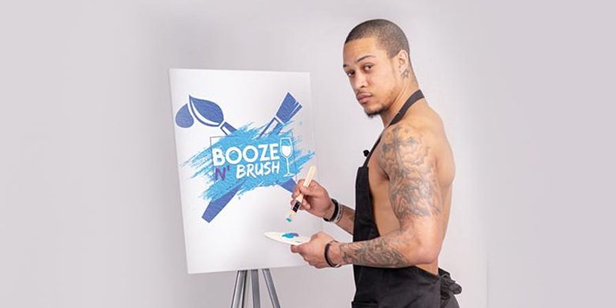 Tattooed man in an apron painting a bright blue paint-and-sip logo on a canvas at an easel in a modern art studio