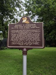 Brown-and-gold historic Louisiana marker in a New Orleans park describing an 1892 Press Street railroad yards segregation arrest, topped with a pelican emblem.