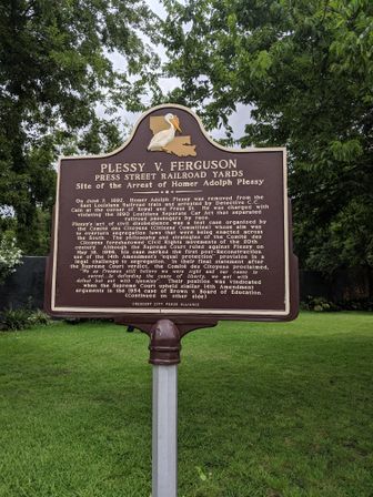 Brown-and-gold historic Louisiana marker in a New Orleans park describing an 1892 Press Street railroad yards segregation arrest, topped with a pelican emblem.