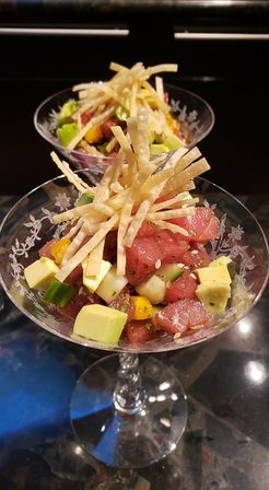 Vibrant ahi tuna poke with avocado, mango and sesame served in a glass coupe, topped with crunchy tortilla strips.