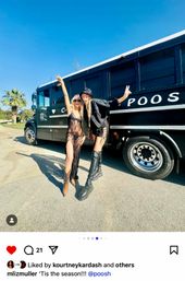 Two smiling women in festival fashion — a sheer maxi dress and lace-up shorts with tall boots — posing with peace signs beside a black party bus under a bright blue sky and palm trees.