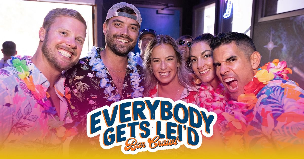 Smiling group of friends in colorful Hawaiian shirts and flower leis posing inside a neon-lit bar during a festive Hawaiian-themed bar crawl.