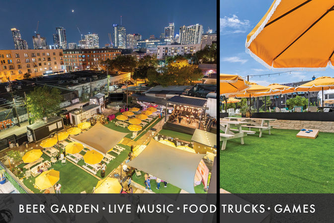 Rooftop beer garden in a downtown skyline setting with yellow umbrellas over picnic tables on green turf, food trucks, a small stage for live music, outdoor games and string lights at dusk.