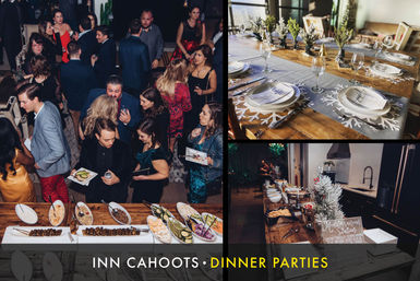 Festive indoor dinner party with guests mingling around a wooden buffet of appetizers, catered stations, and elegant winter-themed place settings.