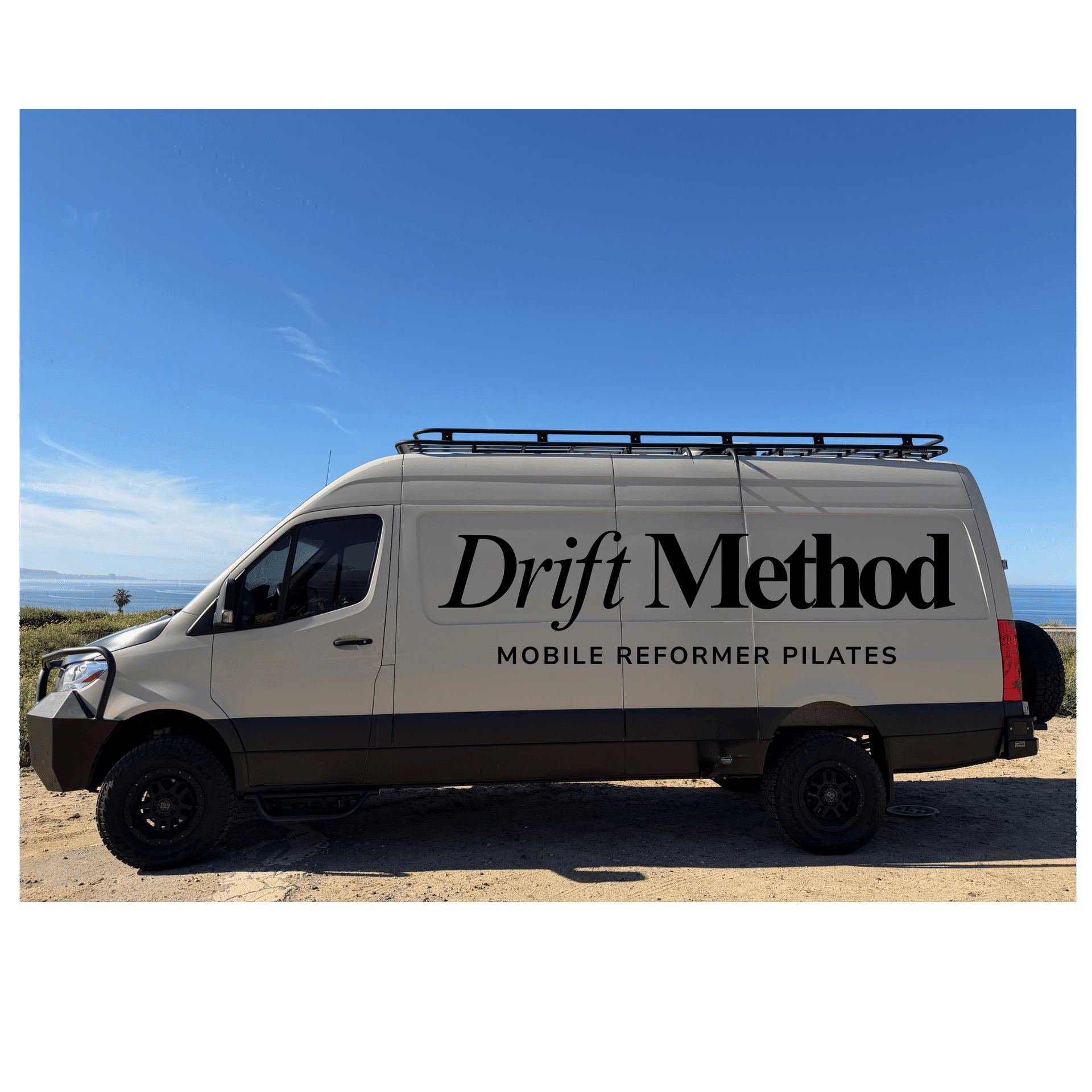 Sunlit coastal scene: beige mobile Pilates van with roof rack and rugged tires parked on a sandy bluff overlooking the ocean, large black lettering advertising mobile reformer Pilates.