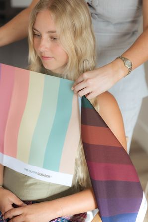 Blonde woman in a styling studio having pastel and deep color fabric draped around her shoulders by a stylist for a personal color consultation