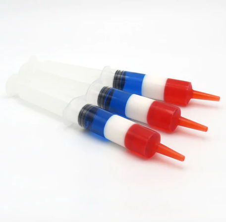 Product photo of three clear plastic dispensing syringes with blue-and-white barrels and bright red nozzle caps angled on a clean white background.