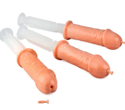 Three novelty flesh-toned penis-shaped plastic syringes with clear plungers, playful adult party gag shot dispensers on a white background
