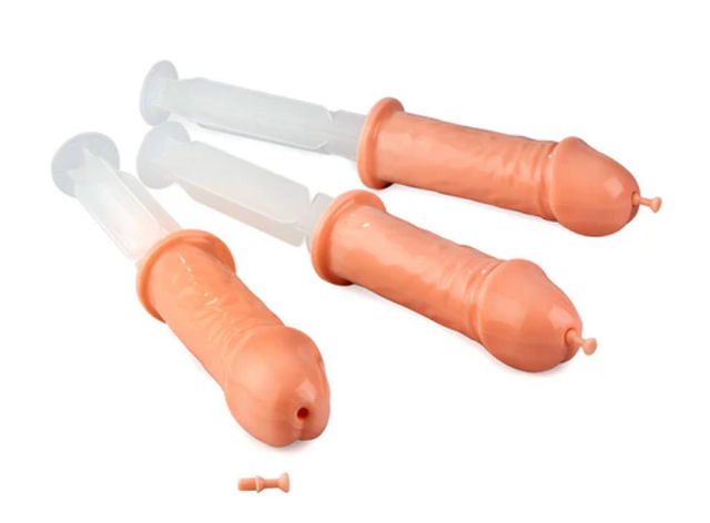 Three novelty flesh-toned penis-shaped plastic syringes with clear plungers, playful adult party gag shot dispensers on a white background
