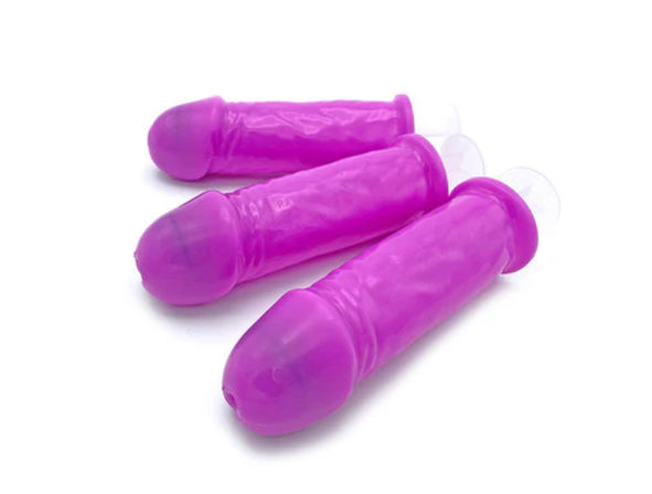 Three bright pink silicone adult novelty popsicle molds shaped like phalluses with clear suction-cup bases on a white background