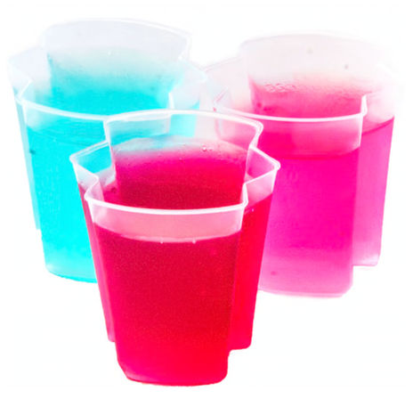 Three flower-shaped plastic cups filled with vibrant pink and turquoise gelatin desserts on a white background, colorful party jello cups.