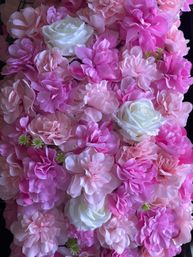 Close-up of a lush pink and white floral wall of artificial roses and peonies, layered petals forming a vibrant wedding or event backdrop