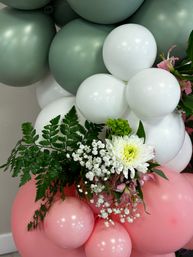 Pastel balloon garland of sage green, white and pink balloons with fern greenery, white chrysanthemum and baby's breath floral accent — party decoration