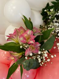 Pink alstroemeria bouquet with baby’s breath and eucalyptus arranged against white and pink celebration balloons