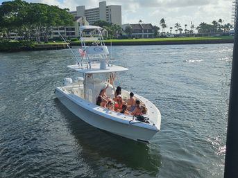 Group of people on a white center-console boat cruising a sunny intracoastal waterway past waterfront condos and palm trees