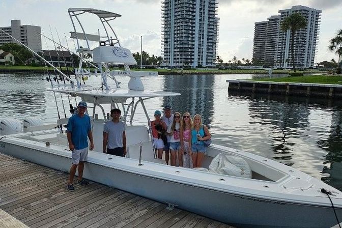 Group of people posing on a center-console fishing boat docked at a waterfront marina with high-rise condo towers in the background
