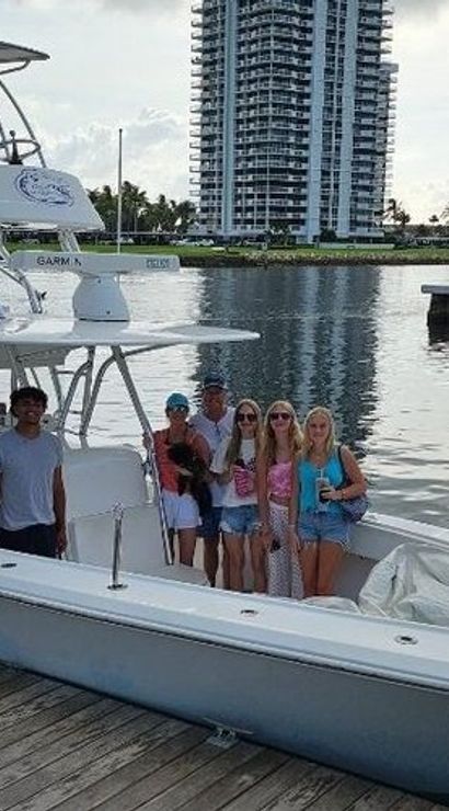 Group of people posing on a center-console fishing boat docked at a waterfront marina with high-rise condo towers in the background