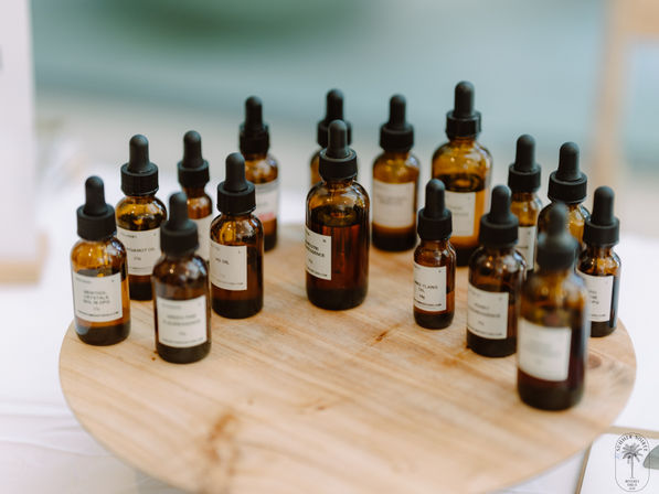 Amber glass dropper bottles of essential oils and serums on a round wooden display — aromatherapy and spa wellness setup.