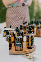 Amber glass dropper bottles labeled "Grapefruit" on a wooden tray at an outdoor aromatherapy market stall — essential oils display.