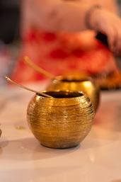 Glittering gold textured condiment bowls with spoons on a restaurant table, warm bokeh background